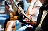 Group of young adult friends using smartphones in the subway. [SHUTTERSTOCK]