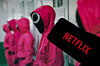 Netflix logo displayed in front of Pink Guards from Squid Game showing the Korean drama that became a top ten regular on Netflix Spain and turned Korean content into the second most watched non English category on the streaming platform worldwide