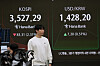 A currency trader passes by a screen showing the Kospi, top left, and the foreign exchange rate between the U.S. dollar and Korean won at the foreign exchange dealing room of the Hana Bank headquarters in Seoul on Oct. 13. [AP/ YONHAP]
