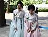 Baik Ji-yeon, left, former anchor and a mother of the groom, and Hong In-hwa, mother of the bride and the wife of HL Group Chairman Jung Mong-won vow before the press at their offsprings' wedding in 2023, wearing blue and pink shade hanbok. [YONHAP]