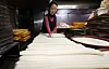 A woman prepares tteok (rice cake) which is used for tteokguk (rice cake soup), a Seollal dish, at a local market in western Seoul on Feb. 11. [NEWS1]