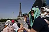 Stephanie Touissaint, foreground, uses a fan to keep cool in the sweltering heat at Eiffel Tower Stadium during a beach volleyball match between Cuba and Brazil in Paris on Tuesday. [AP/YONHAP]
