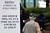 An older adult is seen next to a sign, which informs visitors that smoking, drinking and other indecent acts are not allowed within the park, at Tapgol Park in central Seoul on Aug. 31, 2025. [NEWS1]