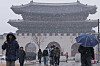 People walk through a flurry of snow at Gwanghwamun Square in Jongno District, central Seoul, on Jan. 13. Snow and rain will continue through Jan. 14 morning in Seoul, with temperatures dropping to minus 5.6 degrees Celsius (21.9 degrees Fahrenheit). [YONHAP]
