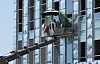 Workers set up a parasol on a boom lift to shield themselves from the sun while working at a construction site in Suwon, Gyeonggi, on July 28. [WOO SANG-JO]
