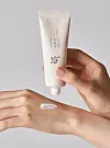 Beauty of Joseon sunscreen tube held above a hand with a dab of cream