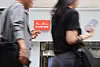 People walk by an SK Telecom store in downtown Seoul on June 24. [YONHAP]