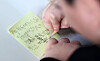 A child writes a memo at an elementary school in Dongdaemun District, central Seoul, on Dec. 24. The message reads, 'I want to work out, get up early, sleep early and eat healthy during the winter vacation.' [NEWS1]