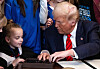 U.S. President Donald Trump speaks with a child as he selects a pen to sign the No Men in Women's Sports Executive Order in the East Room of the White House in Washington, DC, on Feb. 5. [AFP]