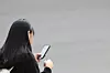A middle school student is seen using her phone on her way home from school at a street in central Seoul on Nov. 4, 2024. [YONHAP]