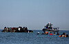 French gendarmes on a boat approach a group of migrants travelling on an inflatable dinghy leaving the coast of northern France in an attempt to cross the English Channel to reach Britain, from the beach of Petit-Fort-Philippe in Gravelines, near Calais, France, on Aug. 25. [REUTERS/YONHAP]