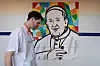 A man walks near a painting depicting Pope Francis at the Gemelli Hospital, where he is admitted for treatment, in Rome, Italy, March 3. [REUTERS/YONHAP]
