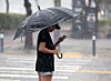 A person wearing an umbrella waits to cross the road in a rainy Seo District, Gwangju, on July 17. [YONHAP]