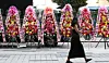 A pedestrian walks by flower wreaths displaying messages demanding BTS's Suga to leave the band in front of HYBE's headquarters in Yongsan District, central Seoul, on Aug. 18. [NEWS1]