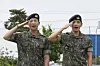 K-pop band BTS members RM, left, and V salute after being discharged from a mandatory military service in Chuncheon, Gangwon, on June 10, 2025. [AP/YONHAP]