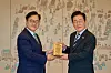 National Assembly Speaker Woo Won-shik, left, presents an award to President Lee Jae Myung at the former presidential office in Yongsan District, central Seoul, on Dec. 3, 2025. The award was made of wooden furniture, which was partially destroyed when troops entered parliament after martial law was imposed a year earlier. [PRESIDENTIAL OFFICE]