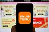 The logo of Chinese e-commerce platform Temu is seen on a mobile phone displayed in front of its website. [REUTERS/YONHAP]