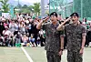 BTS members RM, left, and V salute to fans after finishing their military duties on June 10 in Gangwon. Behind them, fans gathered to congratulate the two singers on their big day. [YONHAP]