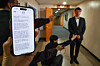 A text message notifying Coupang users that their information has been leaked is seen on a phone with the CEO of Coupang, Park Dae-jun, in the background, at the Seoul Government Complex in central Seoul on Nov. 30. [JOINT PRESS CORPS]