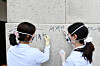 Officials from the National Palace Museum of Korea erase graffiti left on the stone wall of Gwanghwamun on Aug. 11. [NEWS1]