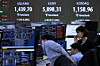 Currency traders work near a screen showing the Kospi top center, and the foreign exchange rate between dollar and won, top center left, at the foreign exchange dealing room of the Hana Bank headquarters in central Seoul on Feb. 23. [AP/YONHAP]