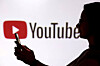 A teenager poses for a photo while holding a smartphone in front of a YouTube logo in this illustration taken Sept. 11. [REUTERS/YONHAP]