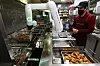A worker supervises a chicken-frying robotic arm installed in a Kyochon store in Namyangju, Gyeonggi, in January 2023. [YONHAP]