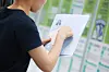 A job seeker browses a job bulletin board while holding a resume at a job fair in Seoul's Gangnam district on June 5. [YONHAP]