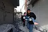 A man carrying a child walks amid the rubble, following an Israeli strike at the Bureij refugee camp in the central Gaza Strip, Palestine, on April 27. [AFP/YONHAP]