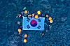 Haenyeo, or female divers, from Jeju and Ulleung islands hold up a large Taegeukgi, or Korean national flag, after performing a diving demonstration off Dokdo on Aug. 8. [JEJU PROVINCIAL GOVERNMENT]