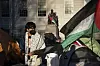 A student protester stands in front of the statue of John Harvard, the first major benefactor of Harvard College, draped in the Palestinian flag, at an encampment of students protesting against the war in Gaza, at Harvard University in Cambridge, Massachusetts, on April 25, 2024. [AP/YONHAP]