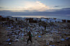 Children walk over a pile of garbage at a makeshift tent camp for displaced Palestinians on a beach in Deir al-Balah, on the Gaza Strip on Jan. 16, 2026. [AP/YONHAP]