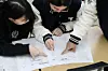 Students check their answers of this year's College Scholastic Ability Test (CSAT) on Nov. 14, 2025, a day after the test took place, at a high school in Daegu. [NEWS1]