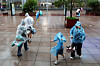 People use umbrellas and raincoats to shield themself from heavy rain and high winds, after Tropical Storm Co-May made landfall in a nearby city, in Shanghai, China on July 30. [REUTERS/YONHAP]