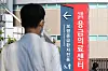 A medical professional stands in front of a vertical signboard indicating the direction to the emergency room at a general hospital in downtown Seoul on Wednesday. [NEWS1]