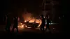 Palestinians walk past a burning car hit in an Israeli strike, in Khan Younis, in the southern Gaza Strip, June 15, 2025. [REUTERS/YONHAP]