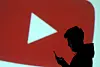 A silhouette of a mobile user is seen next to a screen projection of the YouTube logo in this illustration from March 28, 2018. [REUTERS/YONHAP]
