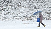 A person walks underneath an umbrella as snow falls in Chuncheon, Gangwon on Dec. 23, 2025. [YONHAP]