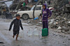 A barefoot boy walks in the rain carrying a plastic jerrycan of water in the Sheikh Radwan neighborhood of Gaza City on Nov. 14. [AP/YONHAP]