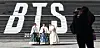 Tourists pose for a photo in front of a promotion for BTS's new album, ″Arirang,″ at the Sejong Center for the Performing Arts in Jongno District, central Seoul, on Jan. 22. [YONHAP]