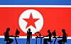 Miniatures of people with computers are seen in front of a North Korea flag in this illustration made on July 19. [REUTERS/YONHAP]