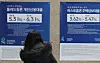 A woman observes signs about a bank's loan programs that were put up on the exterior of a lender in Seoul on March 19. [YONHAP]