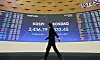 A person walks by the stock board at the Korea Exchange in Yeouido, western Seoul on Jan. 17, the day when the Yoon Suk Yeol administration announced the abolition of a planned capital gains tax on stock trading gains. [YONHAP]