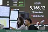 Currency traders watch monitors near a screen showing the Korea Composite Stock Price Index at the foreign exchange dealing room of the Hana Bank headquarters in central Seoul on July 17. [AP/YONHAP]