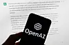 The OpenAI logo is displayed on a mobile phone in front of a computer screen with output from ChatGPT in Boston on March 21, 2023. [AP/YONHAP]