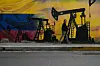 A local walks past a mural featuring oil pumps and wells in Caracas, Venezuela on Jan. 6. [AP/YONHAP]