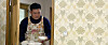 A man in the North Korean drama “A New Spring in the Field of Manchurian Cranes” wears a floral apron as he serves a meal to his wife and daughter. [KOREAN CENTRAL TELEVISION]