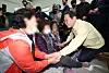 Democratic Party leader Lee Jae-myung, right, holds hands with people displaced by ongoing wildfires at a gymnasium in Uiseong, North Gyeongsang, on March 27. [JOINT PRESS CORPS]