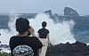 People take photos near the ocean in Seogwipo, Jeju Island, as large waves crash ahead of Typhoon Jongdari's approach on Aug. 20. [YONHAP]