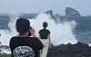 People take photos near the ocean in Seogwipo, Jeju Island, as large waves crash ahead of Typhoon Jongdari's approach on Aug. 20. [YONHAP]